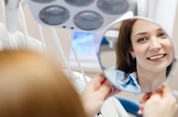 Happy dental patient admiring her smile in the mirror