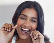 Woman smiling while flossing her teeth