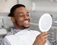 Man smiling at reflection in handheld mirror