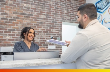 Woman handing dentist a payment card from across a desk