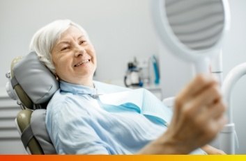 Older woman looking at her smile in mirror at dental office