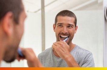 Man smiling while brushing his teeth