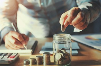 Someone dropping coins into a jar