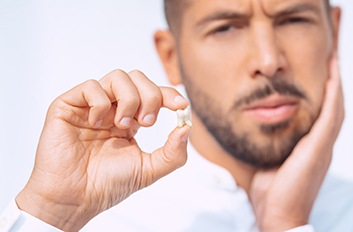 Man holding a tooth after a tooth extraction in Brooklyn, NY