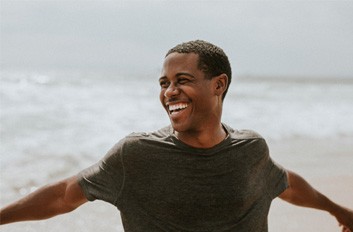 Man walking down the beach on cloudy day and smiling