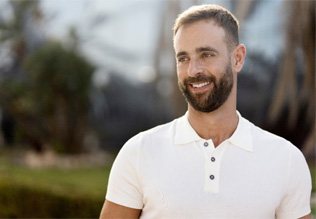 Man in white shirt standing outside and smiling