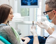 AA dentist showing a dental implant to his patient