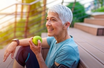 Senior woman eating a green apple outdoors