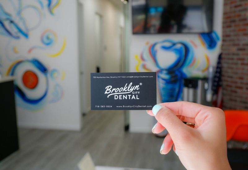 Person holding a business card for Brooklyn City Dental