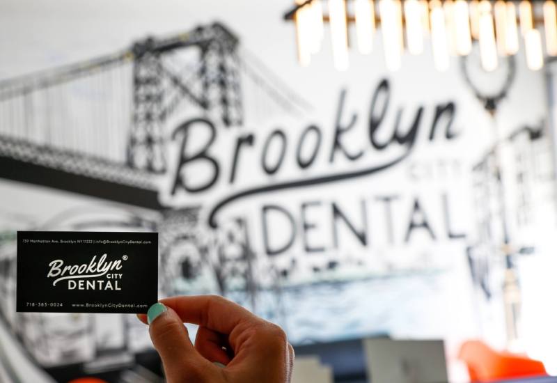 Person holding Brooklyn City Dental business card in waiting room
