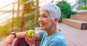 Senior woman eating green apple outdoors