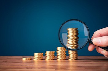 Magnifying glass examines a stack of increasingly larger coins