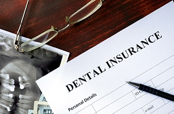 Glasses, X-ray, and cash on desk with dental insurance form