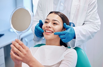 Patient smiling at reflection in handheld mirror