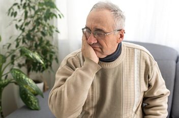 a man holding his cheek due to tooth pain