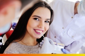 Cosmetic dentist holding veneers in Brooklyn to a young woman's smile