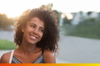 Young woman with curly hair grinning outdoors