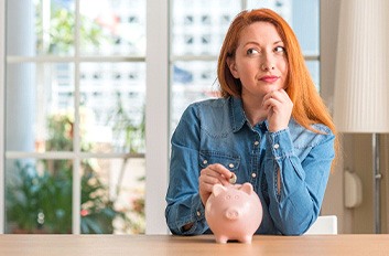 Woman putting a coin into a piggy bank