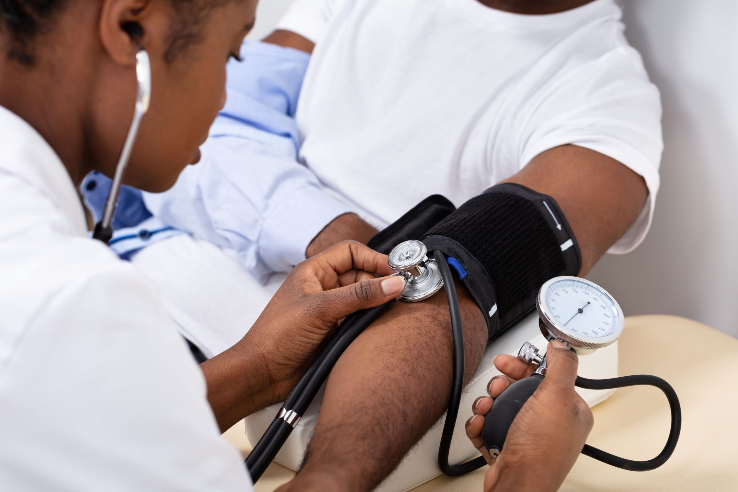 Medical professional taking a man's blood pressure with arm cuff.