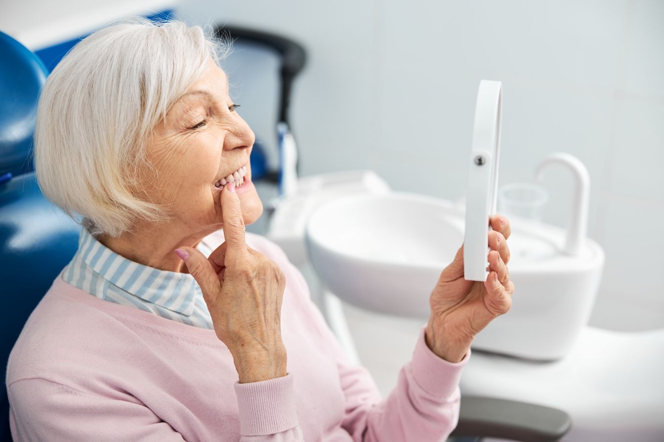 A woman at the dentist looking in the mirror at her smile.