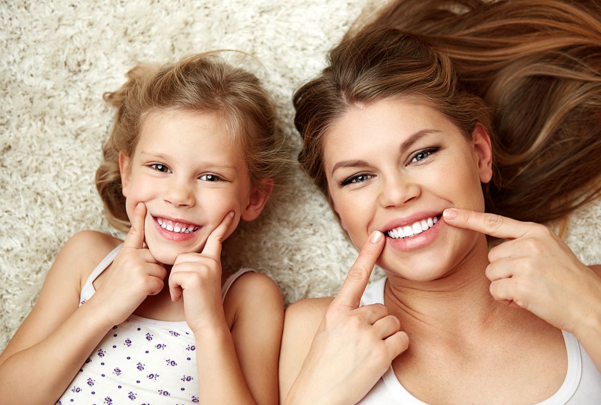 A mother and daughter pointing to their teeth.