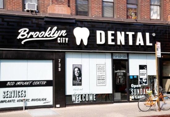Brooklyn City Dental storefront with bold signage featuring a tooth icon. Glass windows display dental services. An orange bike is parked outside.